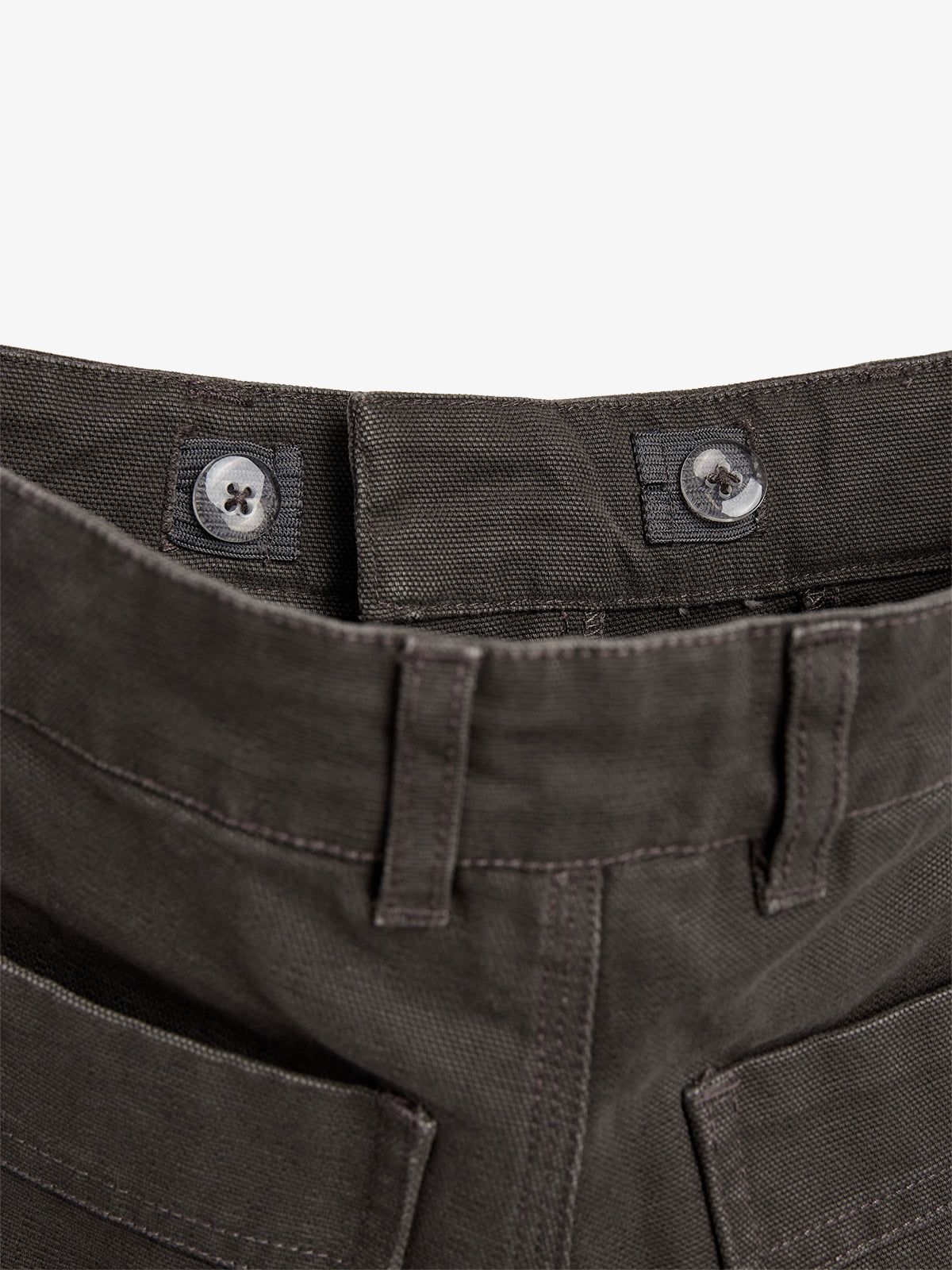 A pair of dark brown pants with button and loop fasteners is laying flat, showing reinforced stitching and belt loops in close-up detail. The background is plain white.