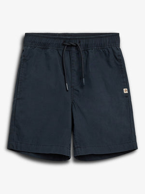 Dark blue shorts are laid flat, featuring an elastic waistband with a drawstring. A small logo patch is visible on the side. They are set against a plain white background.