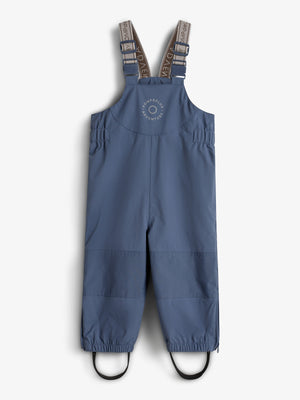 Blue children's overalls with adjustable shoulder straps and elasticized cuffs hang against a plain white background. "ROMPDELUX ADVENTURE" is printed on the chest.