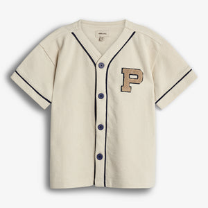 A short-sleeved, cream-colored baseball-style shirt with black piping features black buttons and a large embroidered letter "P" on the left chest. Seen against a plain white background.