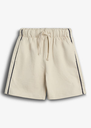 Beige shorts with a drawstring waistband, featuring navy piping along the sides. They are laid flat against a plain white background, highlighting the casual and comfortable design.